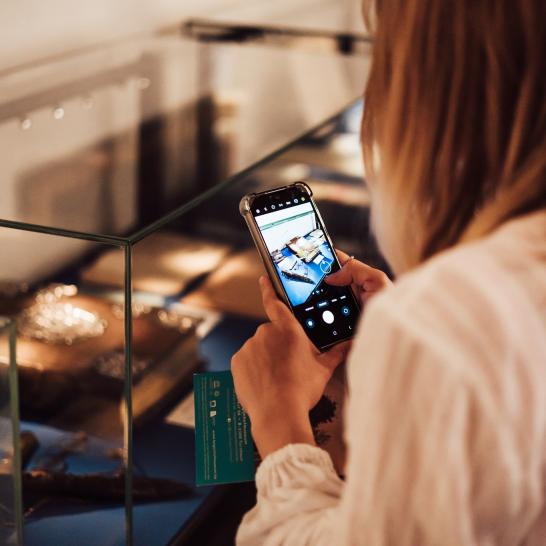 Een bezoeker neemt met haar gsm een foto van een object in het museum