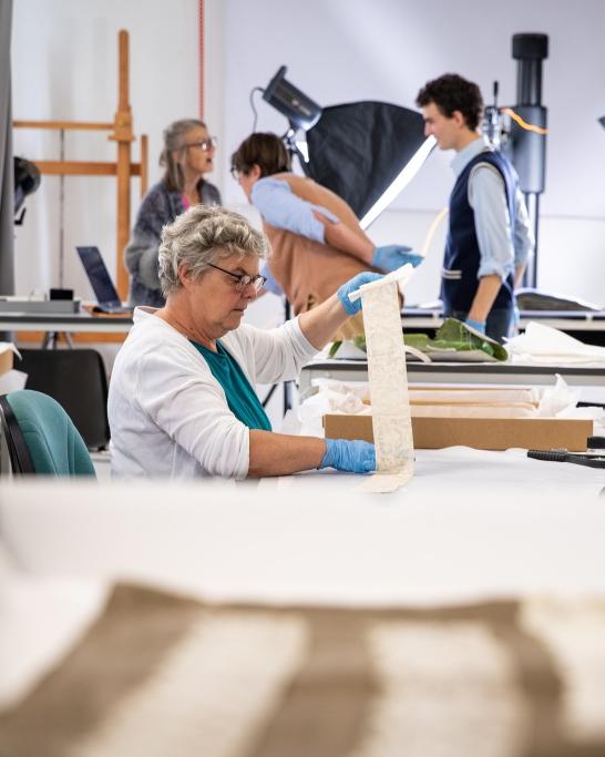 Vrijwilligers zijn aan het werk met kant uit de collectie van het museum