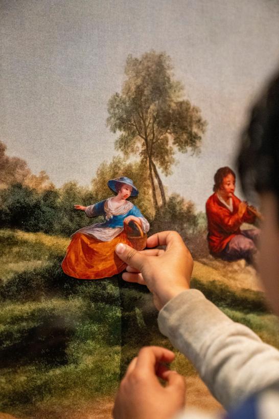 Een kindje plakt een personage in een schilderij in het museum.